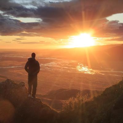 Man stood on mountainside looking at sunset