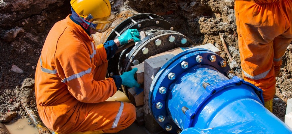 Image shows an engineer repairing a major water pipe
